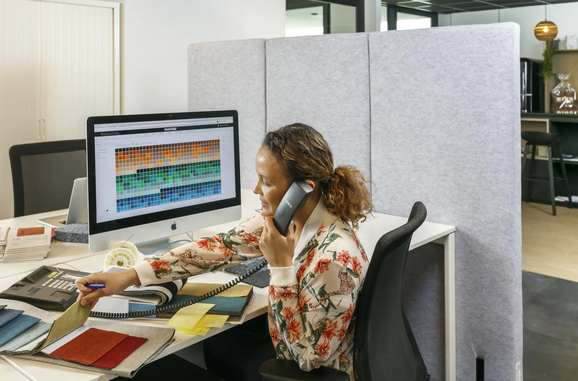 Dame aan het telefoneren op een werkplek met akoestische scheidingswanden