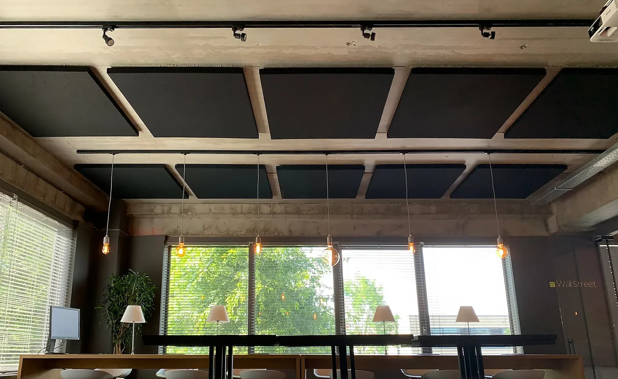 Akoestische plafondpanelen boven werktafels in een kantoor